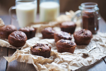 Glass of milk and chocolate cupcakes on a wooden background