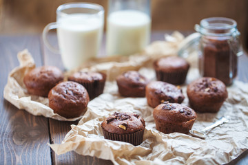 Glass of milk and chocolate cupcakes on a wooden background