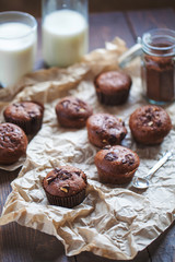 Glass of milk and chocolate cupcakes on a wooden background