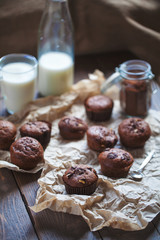 Glass of milk and chocolate cupcakes on a wooden background