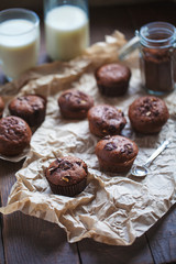 Glass of milk and chocolate cupcakes on a wooden background