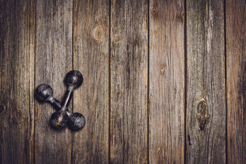 Old iron dumbbells or exercise weights on an old wooden table background. Image taken from above, top view.