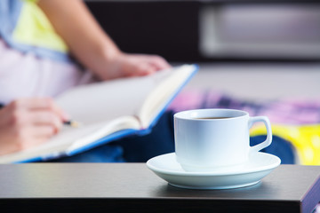 a girl writes down in a notebook sitting on a sofa