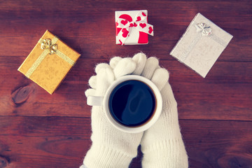 coffee in hands with gifts on a wooden background