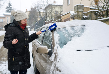 
Woman cleans car outdoor during storm winter snow weather
