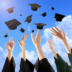 Graduates hands throwing graduation hats in the sky