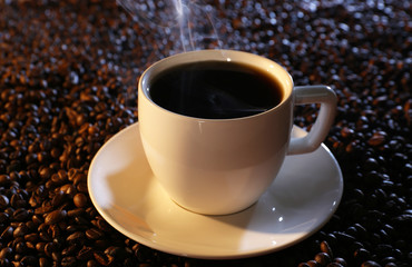 Cup of hot coffee on coffee beans background