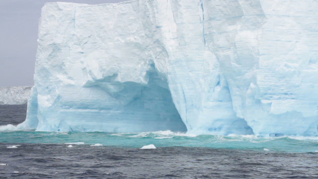 Waves crashing against large tabular iceberg formation in Drake Passage near Antarctica.