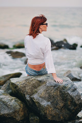 Девушка сидит на камне на берегу моря