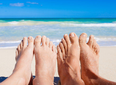 Couples feet on the beach. 