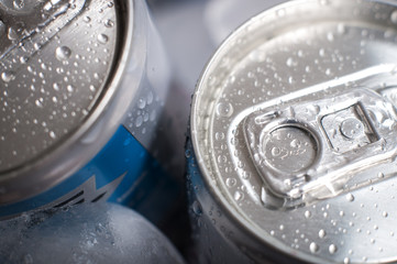 Top of aluminum cans of soda pop covered in ice and droplets of water