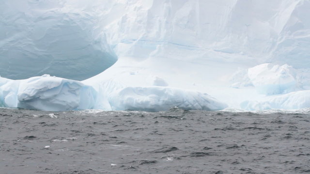 Waves crashing against large tabular iceberg formation in Drake Passage near Antarctica.