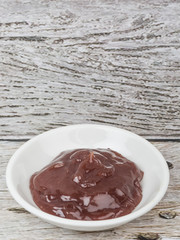 Raspberry fruit curd in white bowl over wooden background