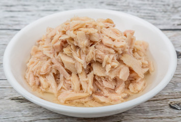 Tuna fish flakes in white bowl over wooden background