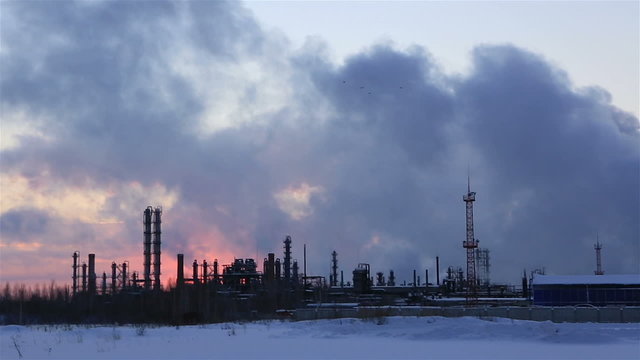 Refinery at sunset sky background. Frosty snowy winter evening. Horizontal panorama