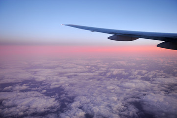 Fototapeta na wymiar pink dawn light on the cloud under the airplane wing