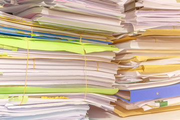 Pile of documents on desk stack up high waiting to be managed
