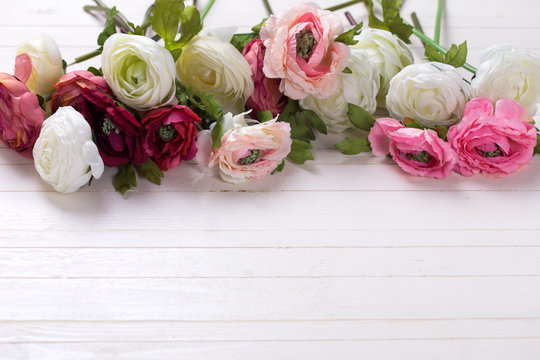 Border from  white and pink flowers  on white wooden background.