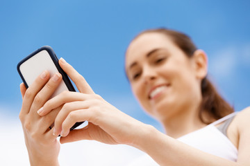 Female runner with her mobile smart phone standing outdoors