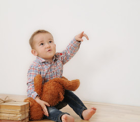 studio shot of little boy point his finger with his toy and book
