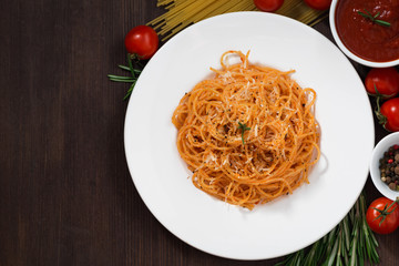 Spaghetti with tomato sauce and ingredients on a wooden table