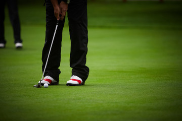 Obraz premium Golf player's legs on green field.