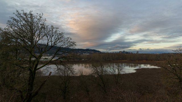 UHD 4k Time lapse movie of moving dark clouds and sunset over Oaks Bottom Wildlife Refuge Pond water reflection and cityscape of Portland Oregon 
