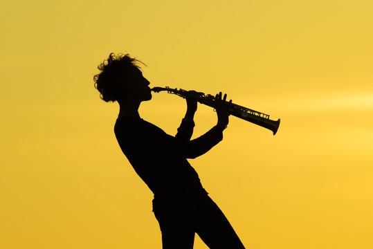 Playing saxophone silhouette on yellow background