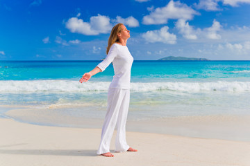 Fototapeta na wymiar Young woman practices yoga on the beach