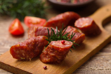 Delicious smoked sausage, sliced on a wooden board with spices.