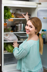 Fototapeta na wymiar long-haired woman arranging space in fridge at home