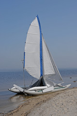 Obraz premium A lone sailboat on the sand on the beach.