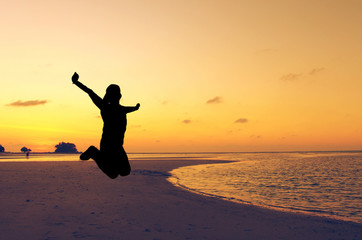 The silhouette of jumping human with sea beach background and orange background