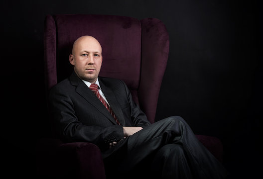 Man sitting in the armchair, dark background