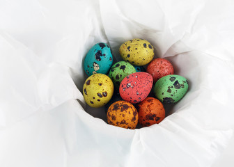 Easter still life. Multicolored quail easter eggs on a white wrapping paper background.