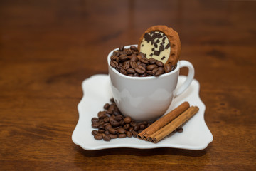 coffee beans cinnamon cookie white cup and saucer on a table brown texture close a lot of grain