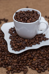 a scattering of coffee beans white cup and saucer on a table brown texture units large lot of grain