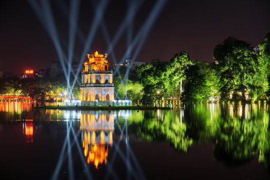 Night view of the Turtle Tower among blue light rays. Hanoi