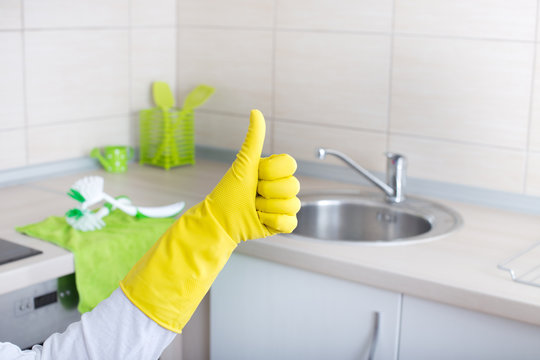 Kitchen cleaning concept - a person wearing yellow gloves and holding a yellow glove