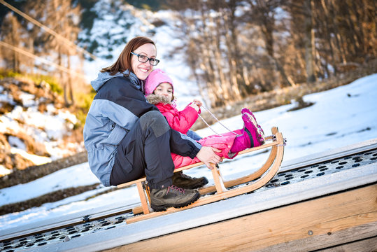 Mother and little child on a ski conveyor on sledge