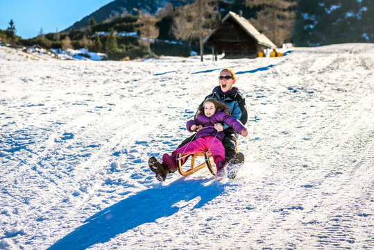 Mother and little child are sledging very fast in ski mountain r