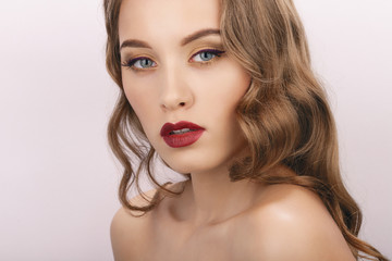 Closeup beauty portrait of young fashionable model with bare shoulders curly hairstyle and trendy gorgeous makeup