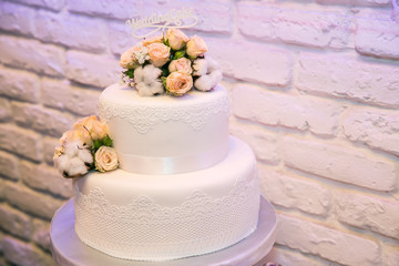 Obraz na płótnie Canvas Multilevel Wedding cake on the table with inscription and flowers, purple light at background