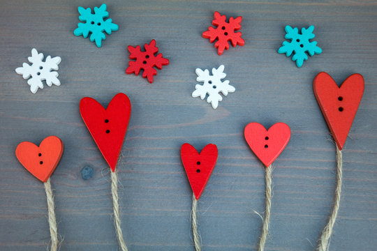 Post card for the Valentine. Button love. Wooden buttons. Button love trees under snowflake on grey wooden background.