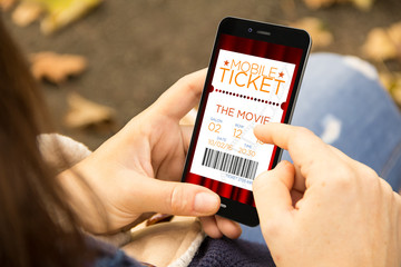 woman reservation cinema e-ticket with a smartphone in the park