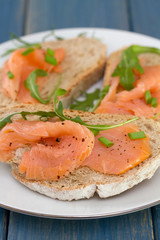 bread with smoked salmon on white plate on blue wooden background