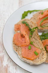 bread with smoked salmon on white plate on white wooden background