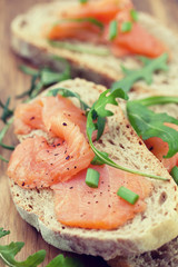 toasts with smoked salmon on brown wooden background