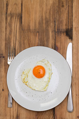 fried egg heart on white plate on brown background