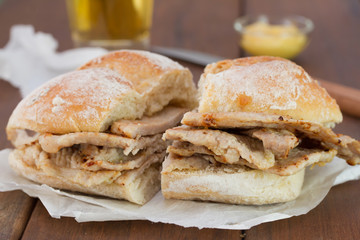 bread with meat on brown wooden background and glass of beer